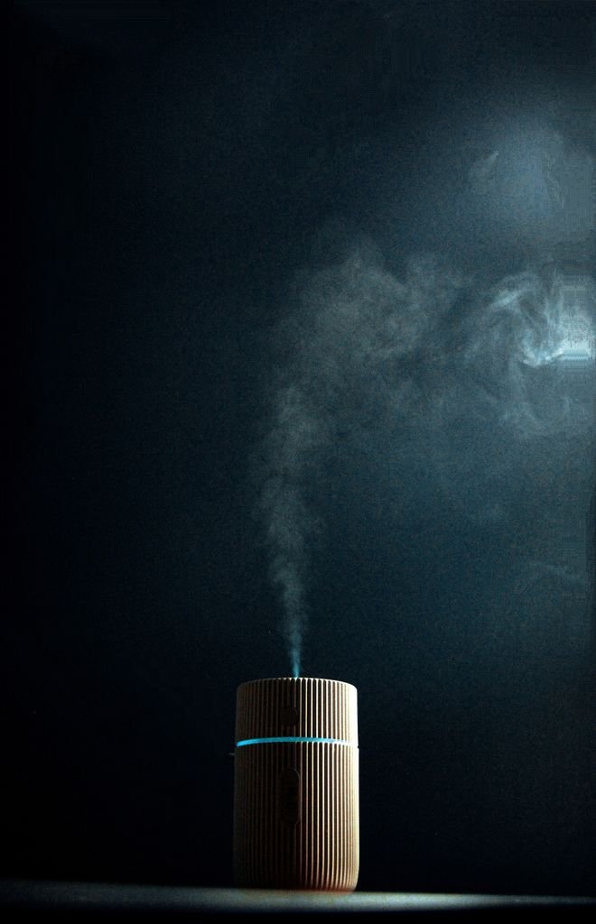 Wooden fragrance diffuser emitting steam against a dark background, creating a soothing ambiance.